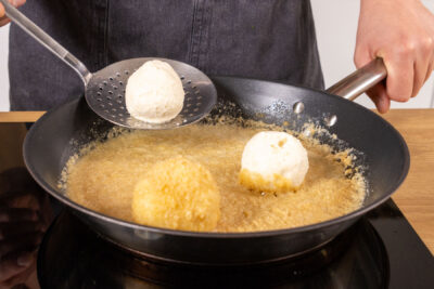 Topfenknödel in die Bröselbutter geben