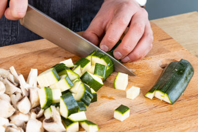 Pilze und Zucchini in Würfel schneiden