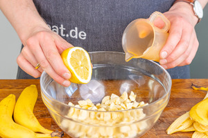 Bananenquark zubereiten: Zitronensaft, Milch und Honig kommen zu den Bananenstücken in die Glasschüssel