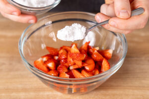 Puderzucker zu den Erdbeeren geben