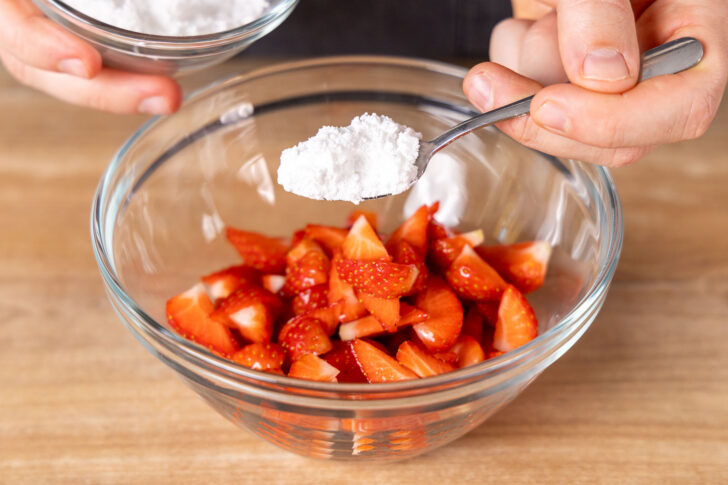 Puderzucker zu den Erdbeeren geben