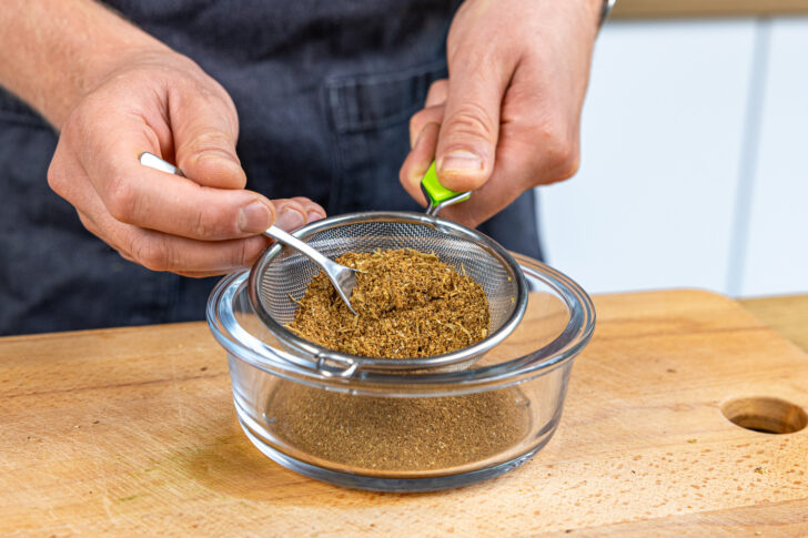 Garam Masala Gewürz durch ein Sieb geben