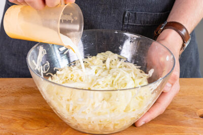 Sahne, Weißweinessig und Öl zum Krautsalat geben