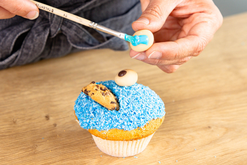 Marzipanauge mit Zuckerglasur am Muffin festkleben