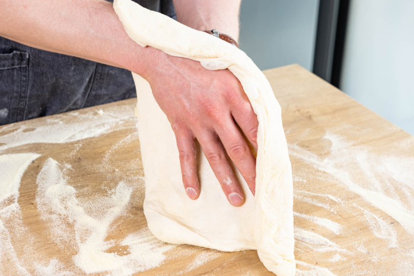 Pizzaboden mit den Händen auseinander ziehen