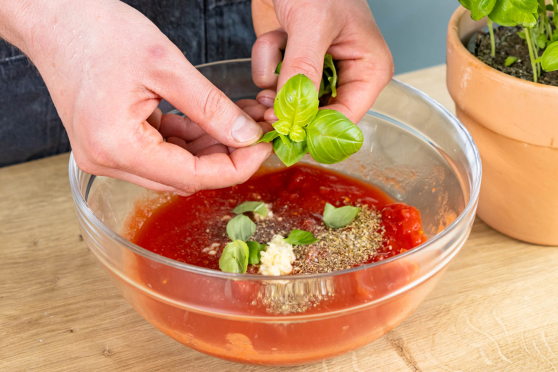 Tomatensoße mit Basilikum, Knoblauch und Gewürzen mischen