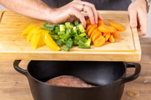 Gemüse und Orangen zum Fleisch geben