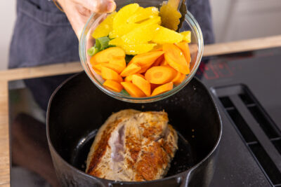 Gemüse und Orange zum Fleisch geben