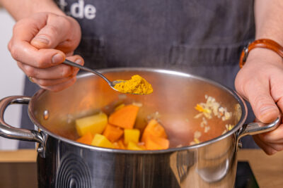Currypulver in den Topf geben