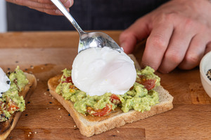 pochiertes Ei aufs Toast geben