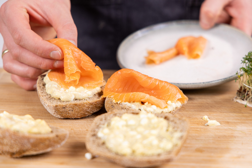 Lachs auf den Brötchen verteilen