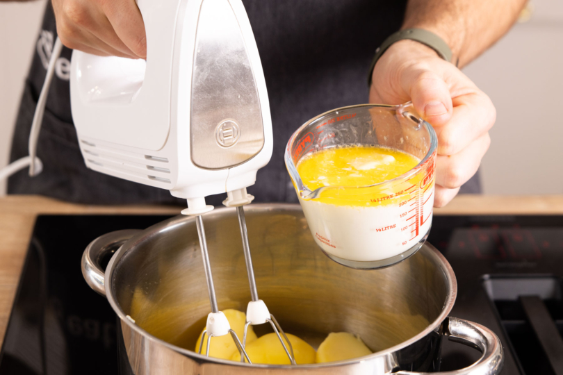 Butter und Milch zu den Kartoffeln geben.