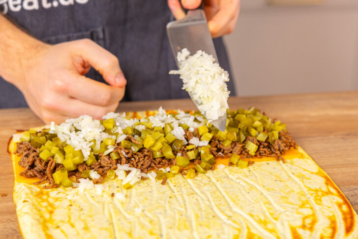 Zwiebeln auf die Cheeseburger Roll geben