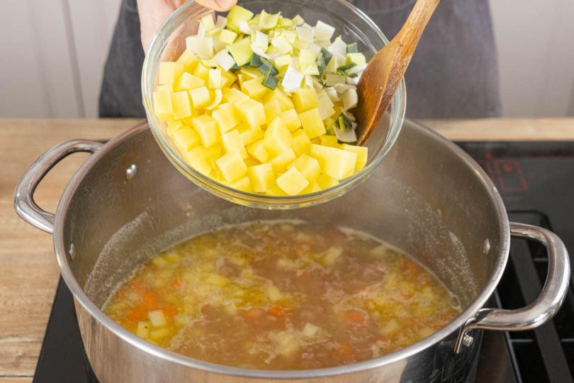 Kartoffeln und Lauch zum Eintopf geben