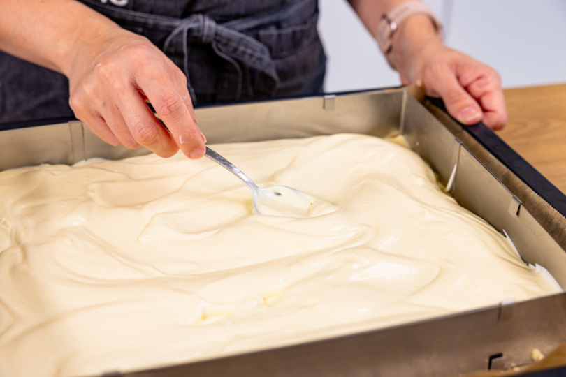 Pudding-Schmand-Creme gleichmäßig auf Mürbeteig verstreichen