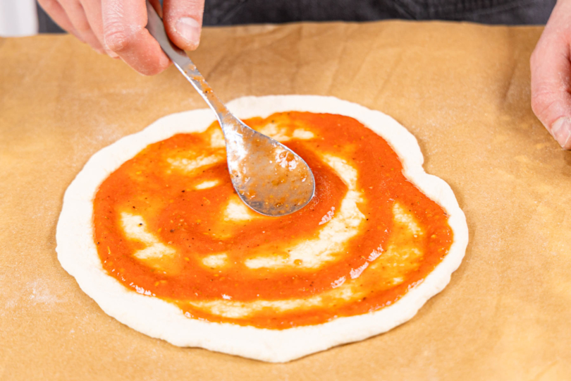 Pizzaboden mit Tomatensauce einstreichen