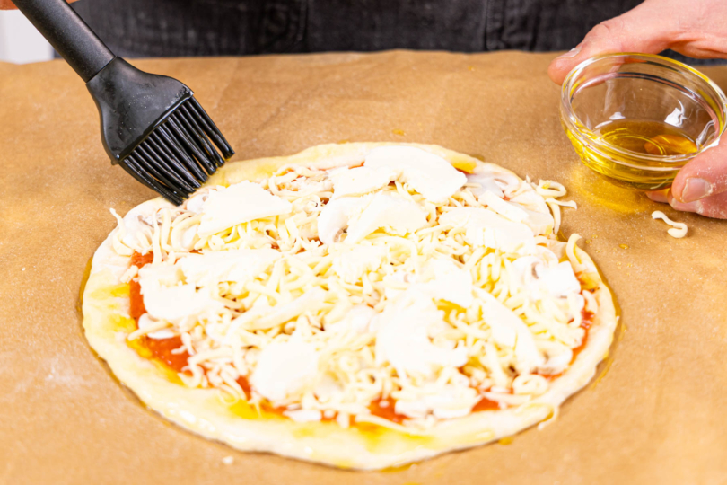 Pizza Funghi belegen und den Rand mit Olivenöl einstreichen und Pizza backen