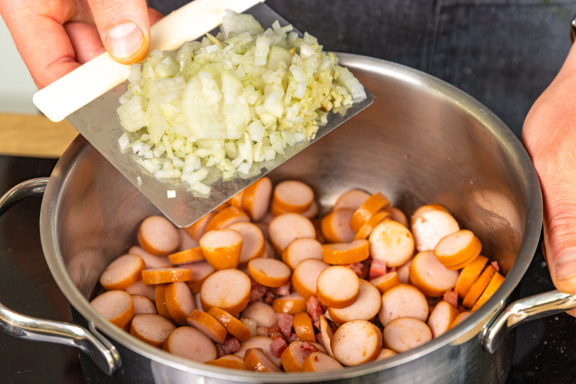 Zwiebeln und Knoblauch in den Topf geben