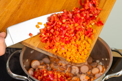 Paprika- und Karottenwürfel in den Topf geben