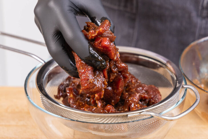 Beef Jerky über einem feinen Sieb abtropfen lassen