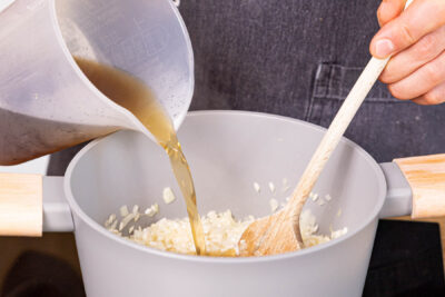 Gemüsebrühe portionsweise zum Risotto gießen und einkochen lassen