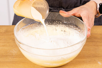 Mehl und Milch dazugeben und zu einem gleichmäßigen Teig verrühren