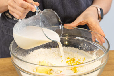 Hefemilch in die Schüssel mit Mehl gießen