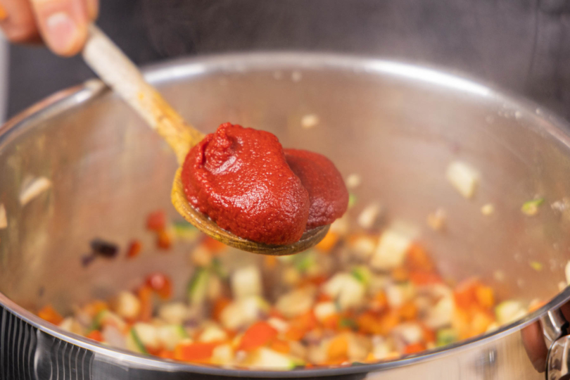 Tomatenmark in den Topf geben