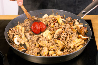 Tomatenmark und Senf zum Jägertopf geben und anschwitzen