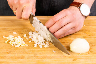 Zwiebel und Knoblauch schälen und in feine Würfel schneiden