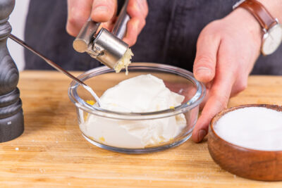 Knoblauch zu dem Schmand geben