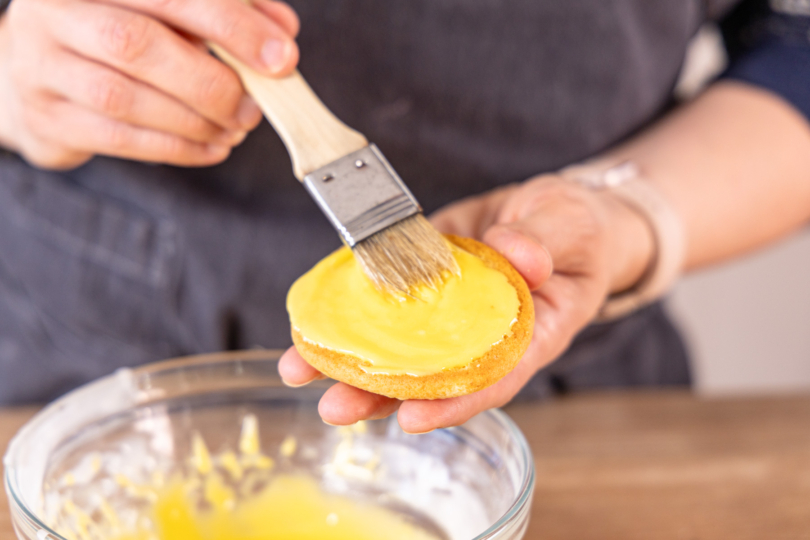 Amerikaner mit gelbem Zuckerguss bestreichen