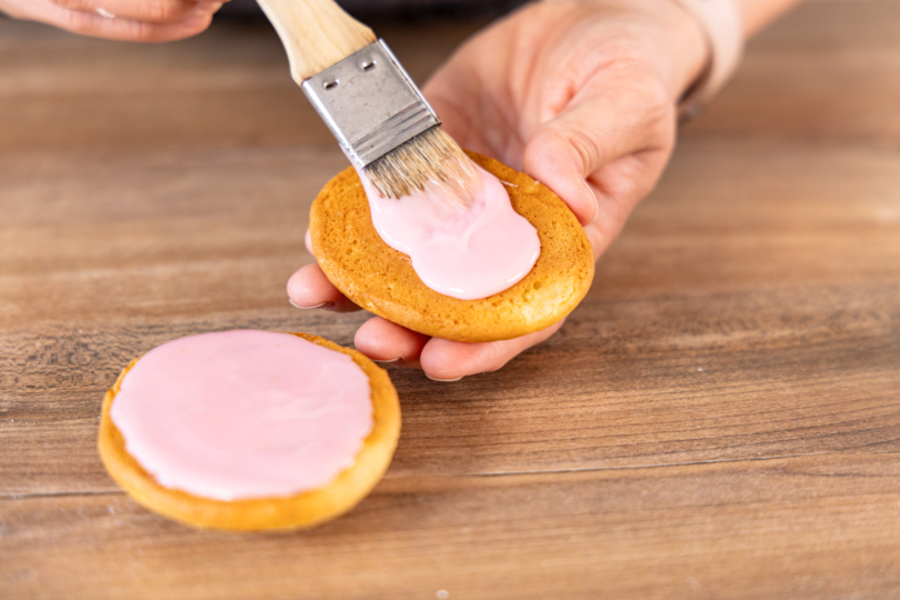 Amerikaner mit rosa Zuckerguss bestreichen
