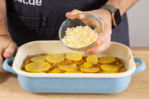Kartoffelauflauf mit Hackfleisch mit Käse bestreuen.
