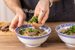 Pho Bo mit Frühlingszwiebeln toppen