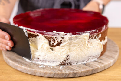 Rand der Stracciatelle-Kirsch-Torte mit Sahne einstreichen