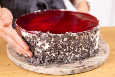 Sahnerand der Stracciatelle-Kirsch-Torte mit Raspelschokolade dekorieren