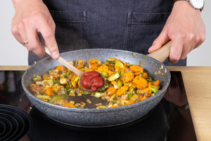Tomatenmark zu dem Gemüse geben.
