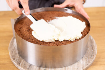 Sahne auf die Oberfläche der Stracciatelle-Kirsch-Torte streichen