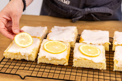 Zitronenscheiben auf den Zitronen-Buttermilch-Kuchen legen
