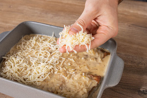 Reibekäse über die Zwiebel-Sahne-Schnitzel mit Zwiebelsuppe geben