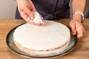 Kokosraspel über Raffaello®-Torte streuen