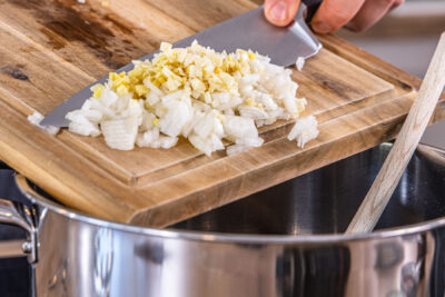 Zwiebel und Knoblauch in den Topf geben