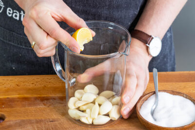 Salz und Zitronensaft zum Knoblauch geben