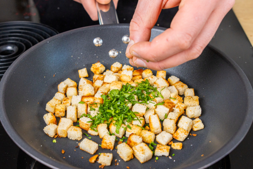 Gehackte Petersilie über Croutons geben
