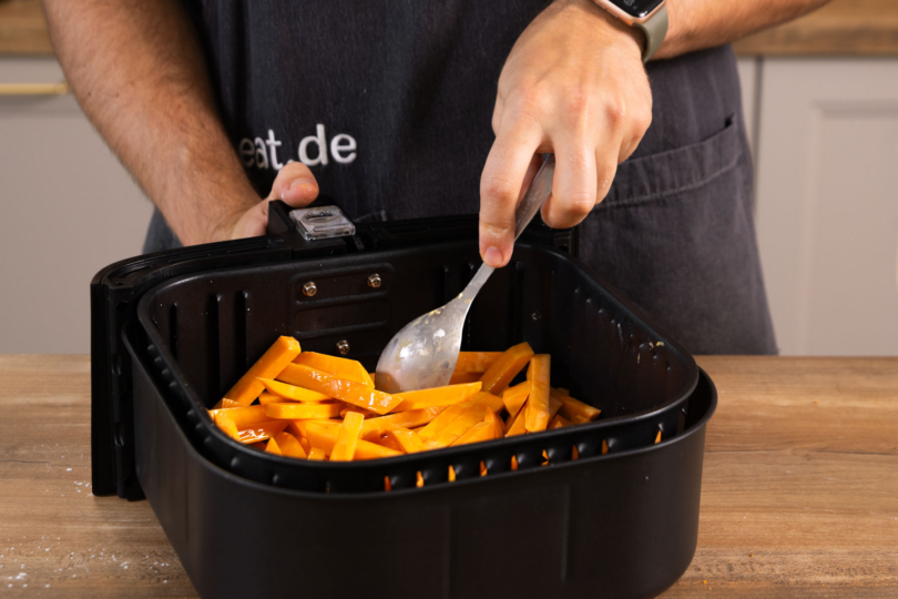 Süßkartoffelpommes in der Heißluftfritteuse verteilen.