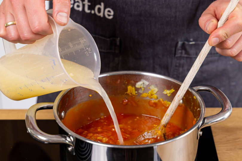 passierte Tomaten und Hühnerbrühe in den Topf geben