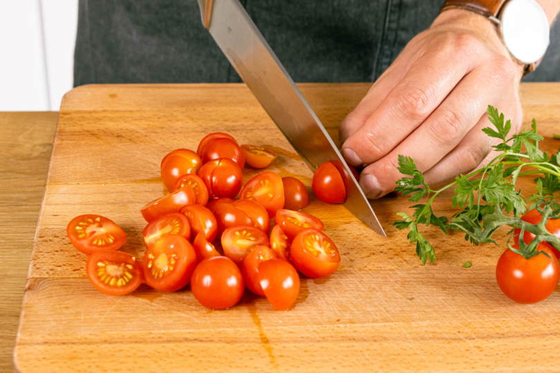 Tomaten halbieren und Kräuter hacken