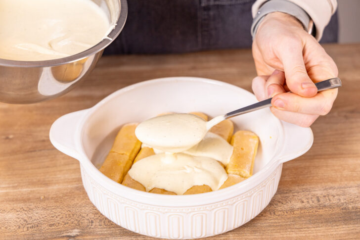 Creme auf Löffelbiskuit verteilen