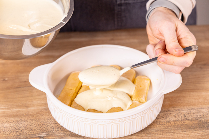 Creme auf Löffelbiskuit verteilen